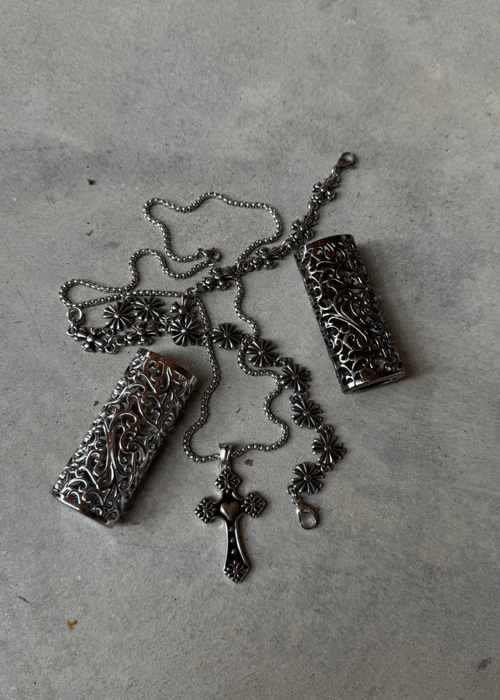 Bloom Cross Necklace styled with ornate accessories, highlighting the intricate floral engravings and polished stainless steel design.