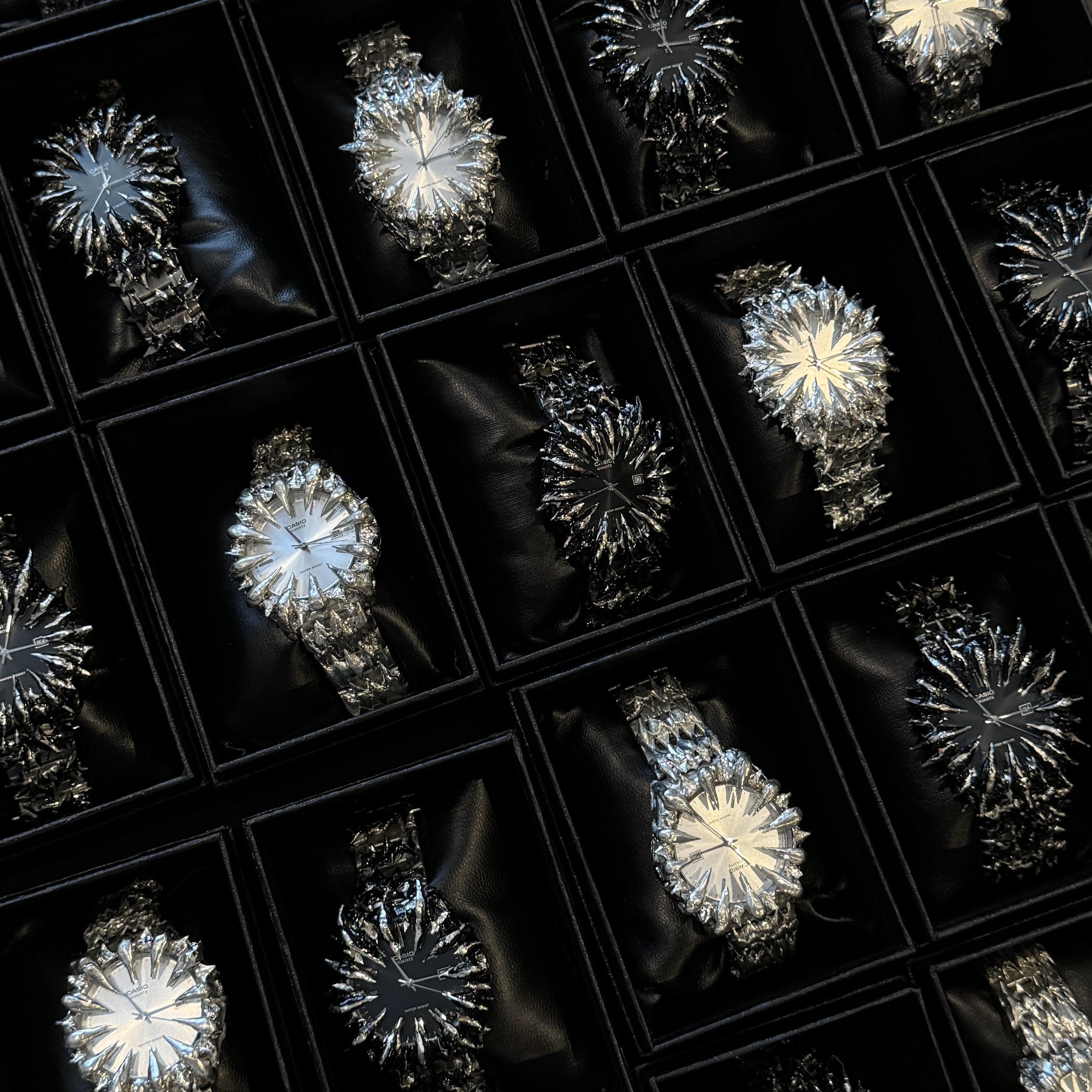 Luxury chrome watches with intricate, spiked crystal designs in display boxes.
