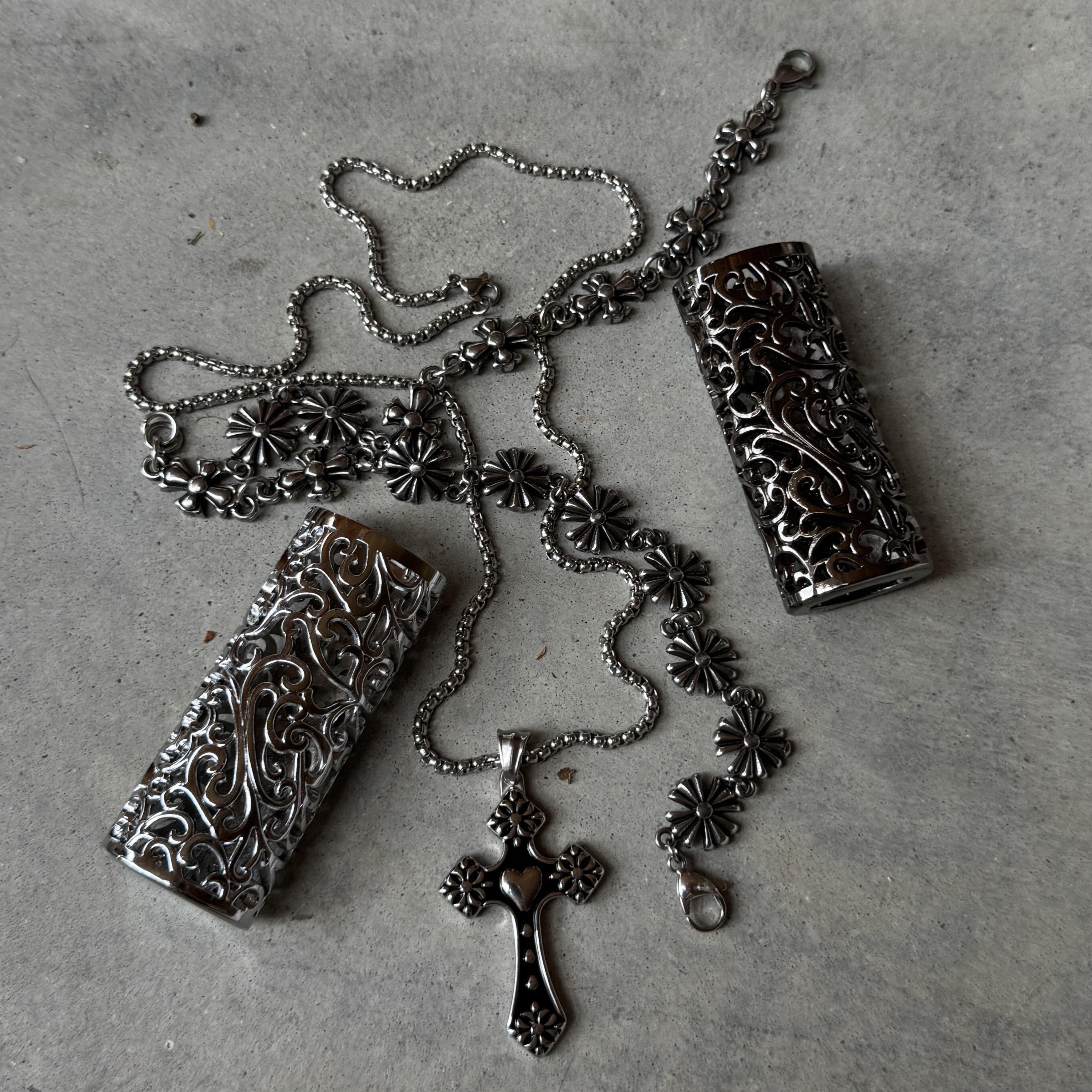 Ornate silver accessories with floral and cross designs on gray background.